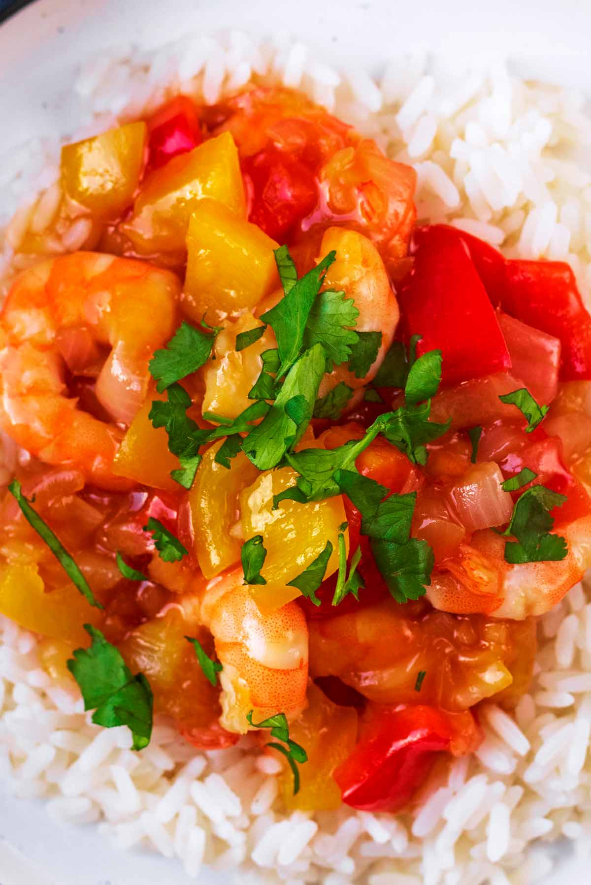 Sweet and sour prawns topped with cilantro leaves on a bed of rice.