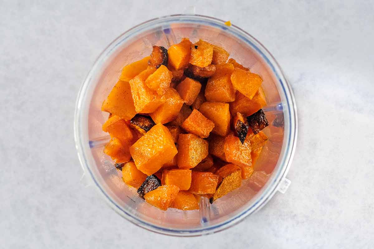 A blender jug containing cubes of roasted butternut squash.