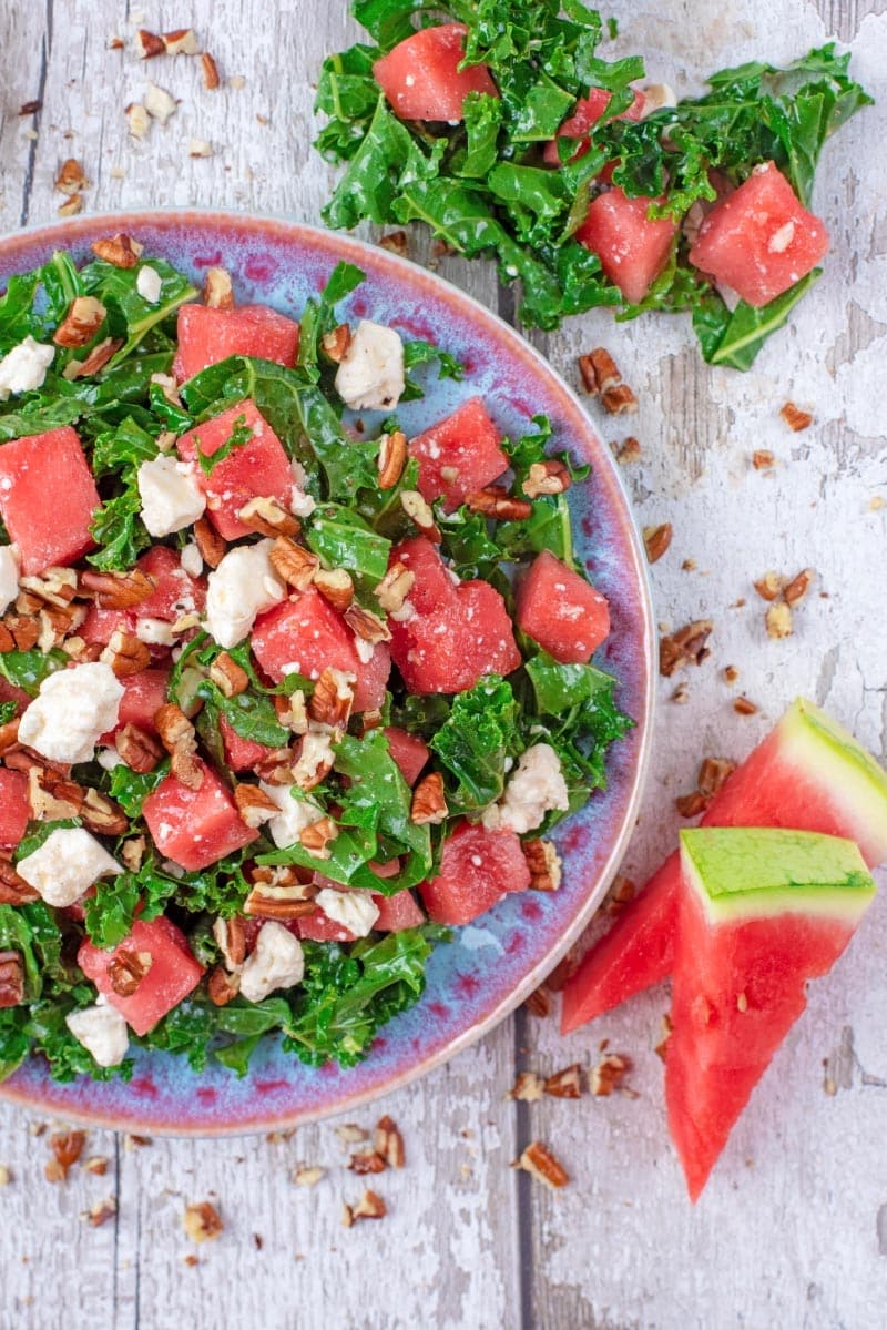 A salad made up of kale, watermelon and feta cheese on a blue plate.