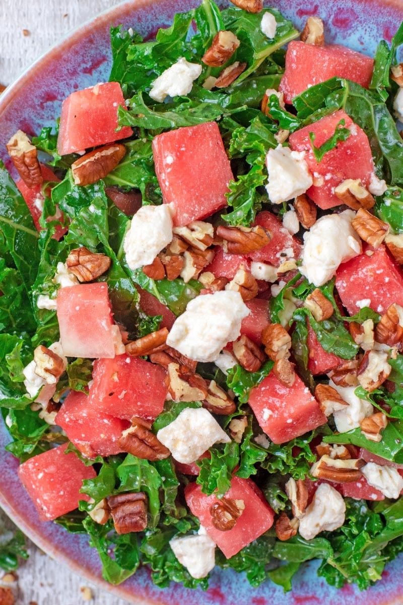 Cubes of watermelon, crumbled feta and chopped pecans on a bed of kale leaves.