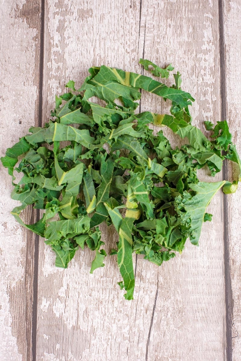A pile of curly kale on a wooden board.
