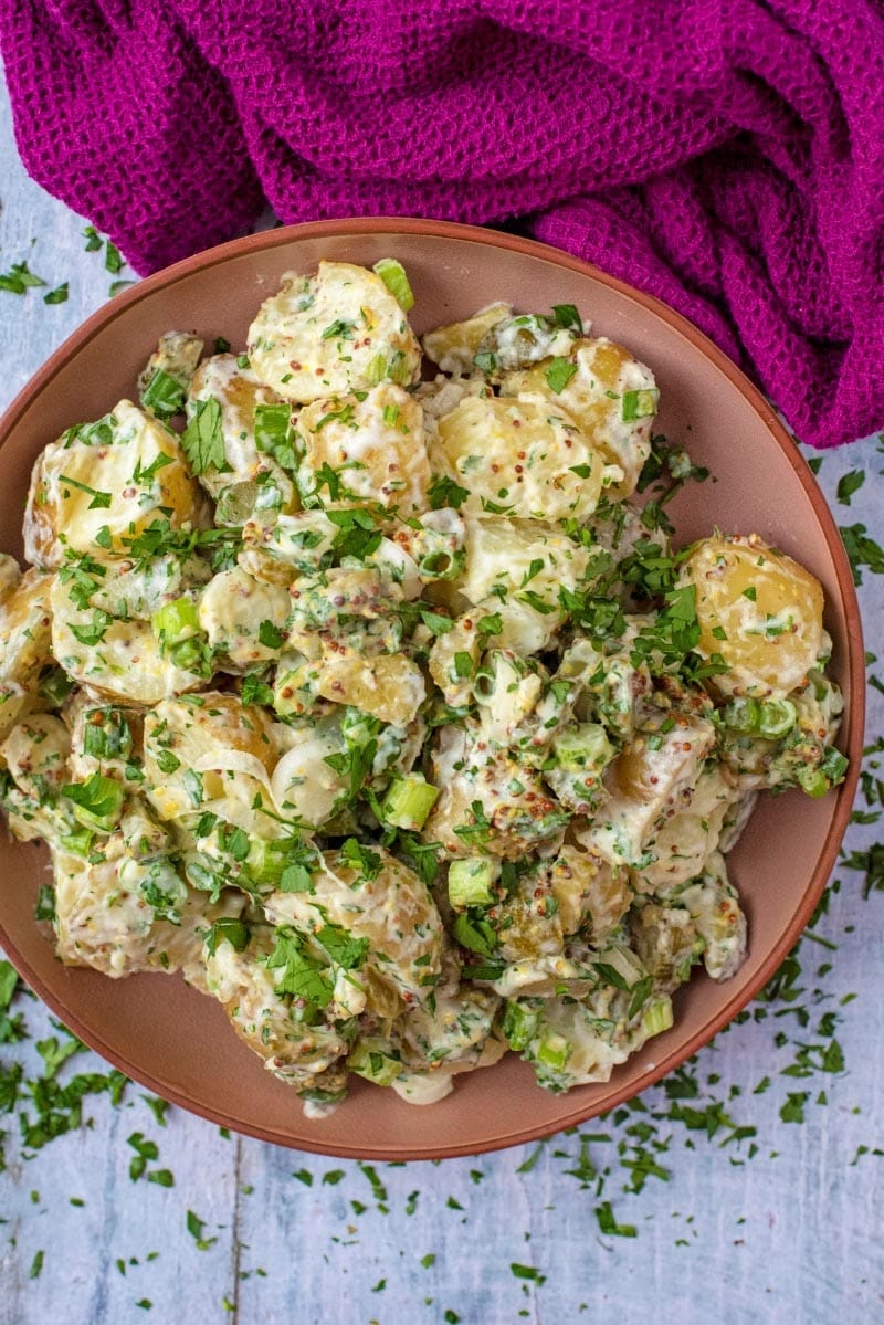 A bowl of potato salad with a purple towel.