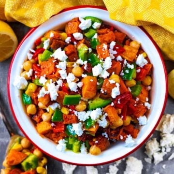 Roasted Sweet Potato Salad in a bowl next to some lemons and a yellow towel.