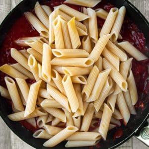 Cooked pasta in a frying pan on top of a tomato souce
