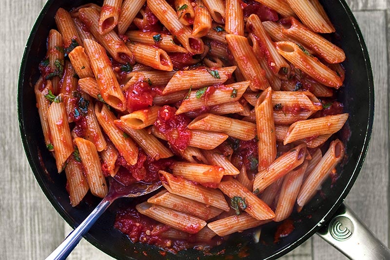 Cooked penne pasta mixed with arrabbiata sauce