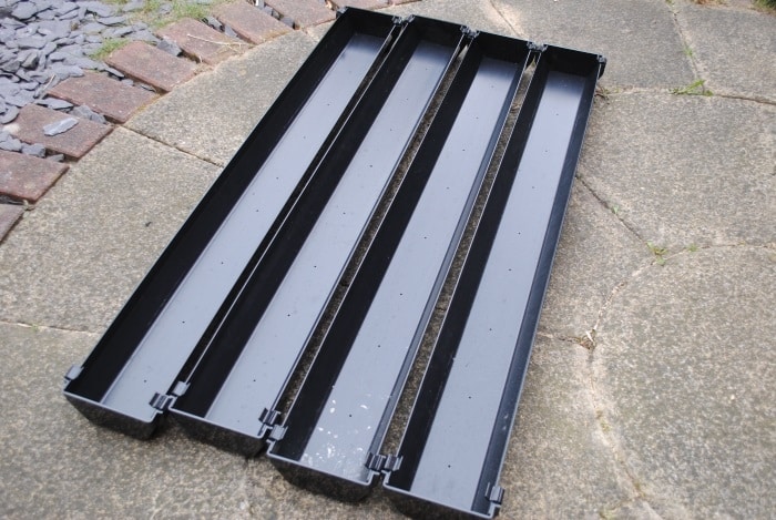 Four lengths of black square line guttering all with stop end on and holes drilled in the guttering.
