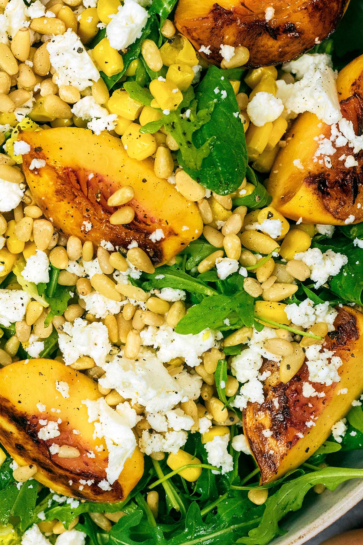 Sliced, grilled peaches, pine nuts and crumbled feta cheese on top of dressed salad leaves.
