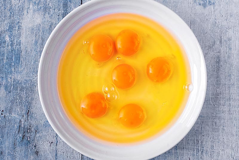 A large bowl with six eggs cracked into it.
