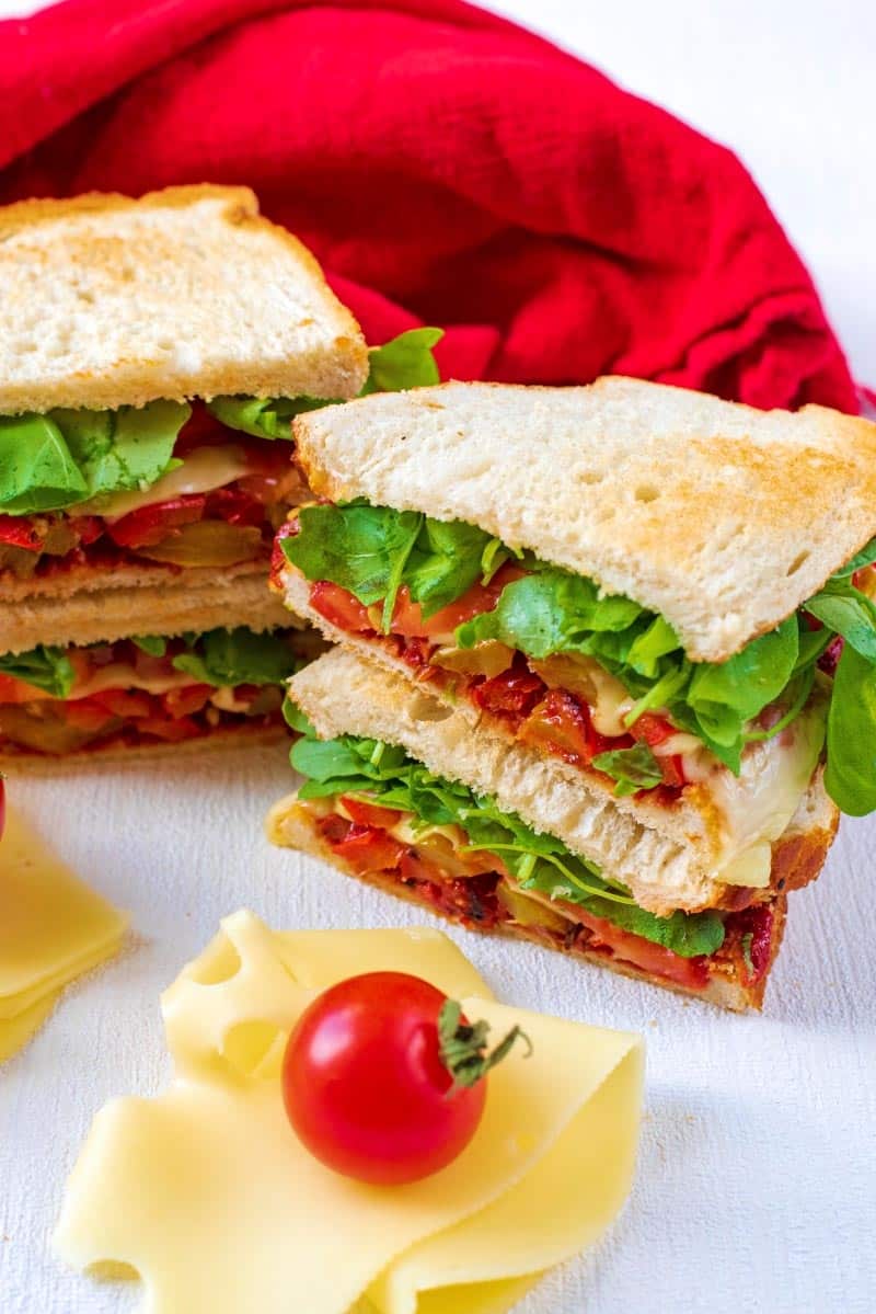 Stacks of sandwiches with a slice of cheese and tomato.
