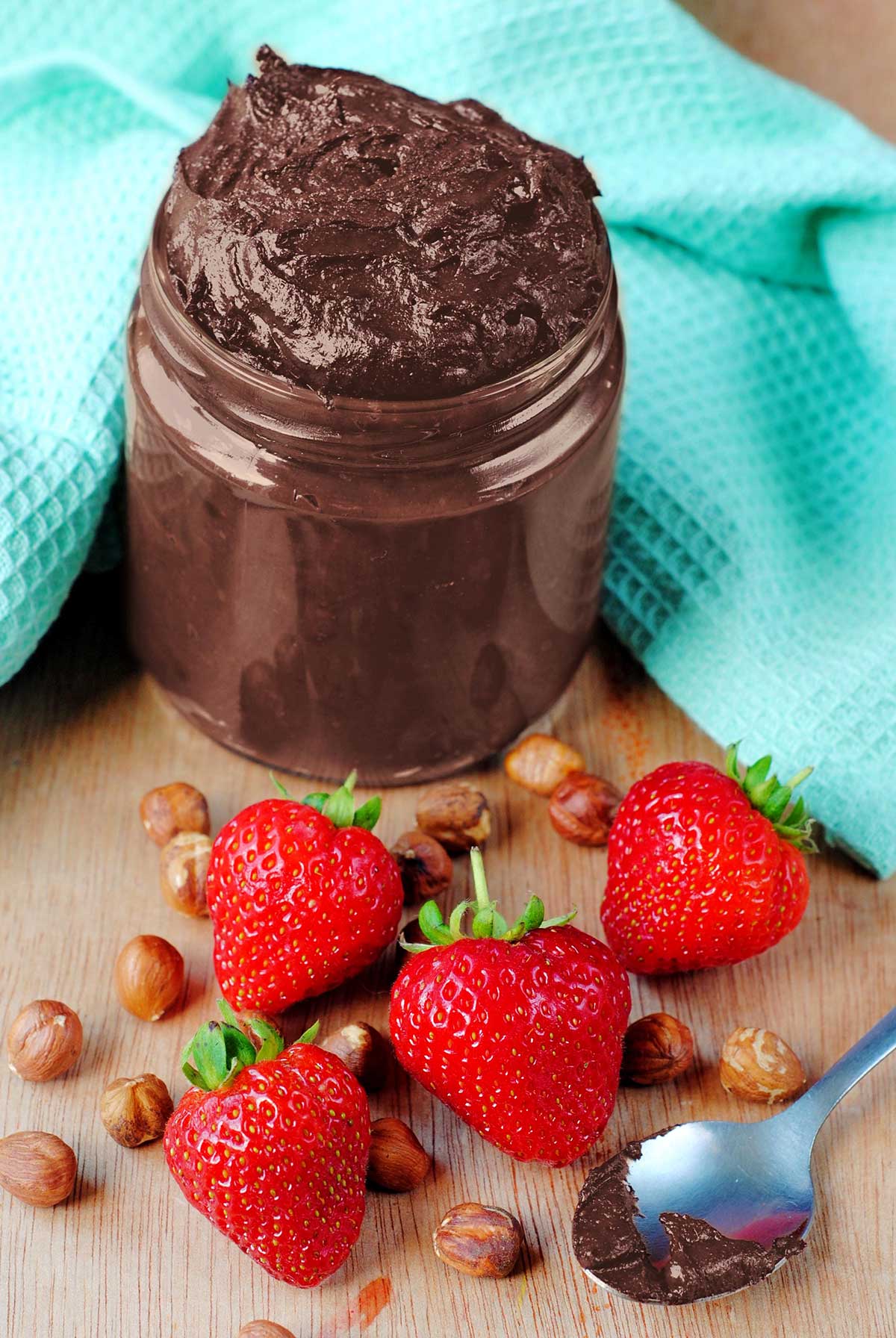 A jar of homemade nutella with some strawberries.