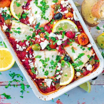 Cod bake in a baking dish topped with chopped herbs and lemon slices