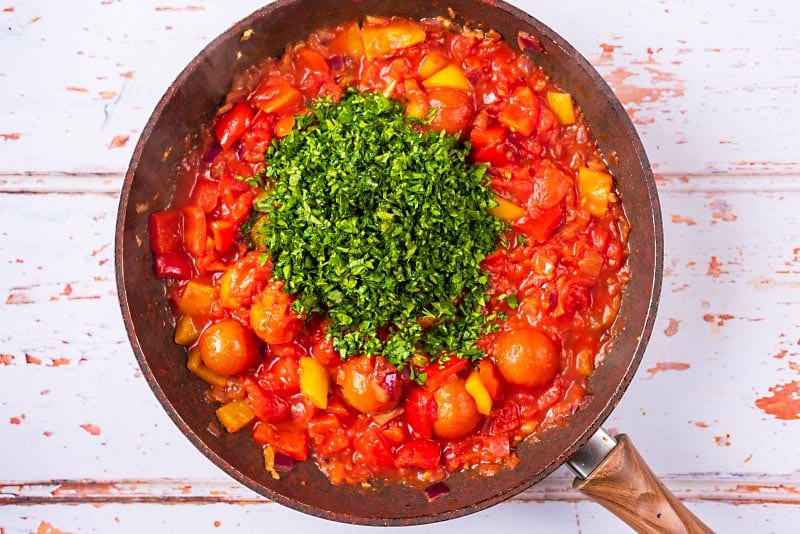 A vegetable tomato sauce and herbs in a frying pan.
