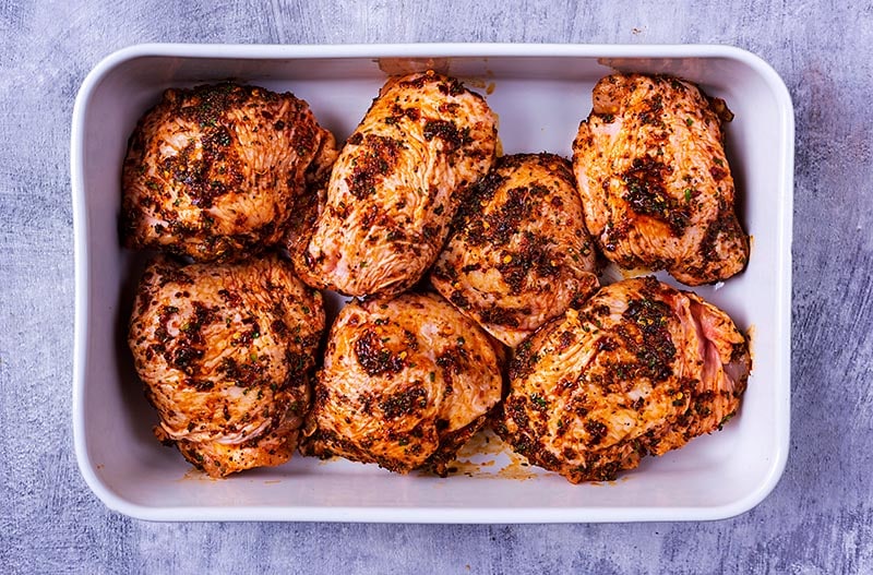 Marinated chicken thighs in a baking dish.