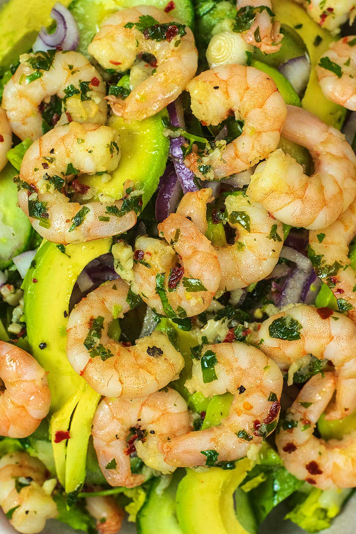 Marinated prawns on top of avocado and salad leaves.