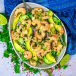 A bowl of prawn avocado salad next to a blue towel.