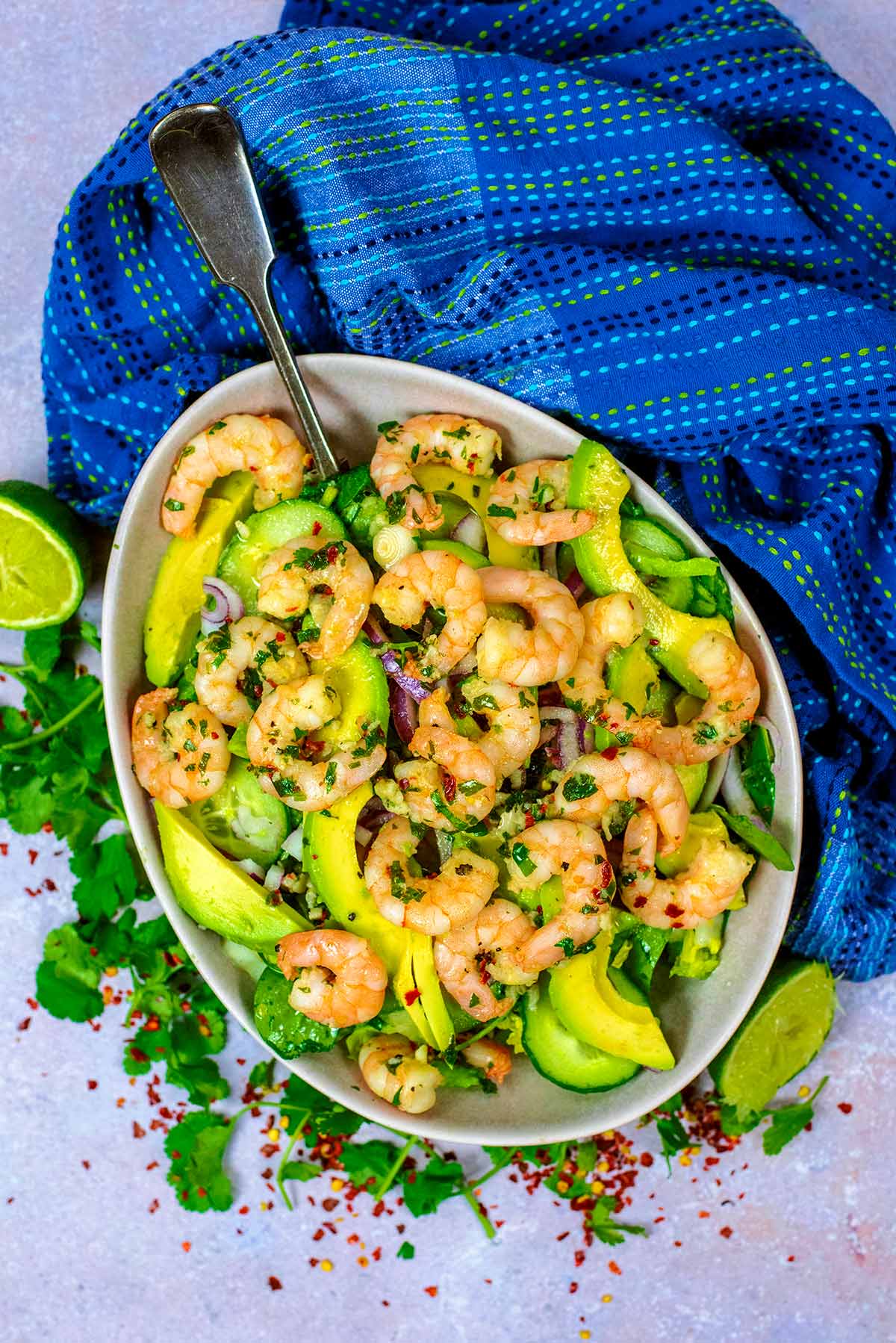 A large bowl of prawn salad next to a blue towel.