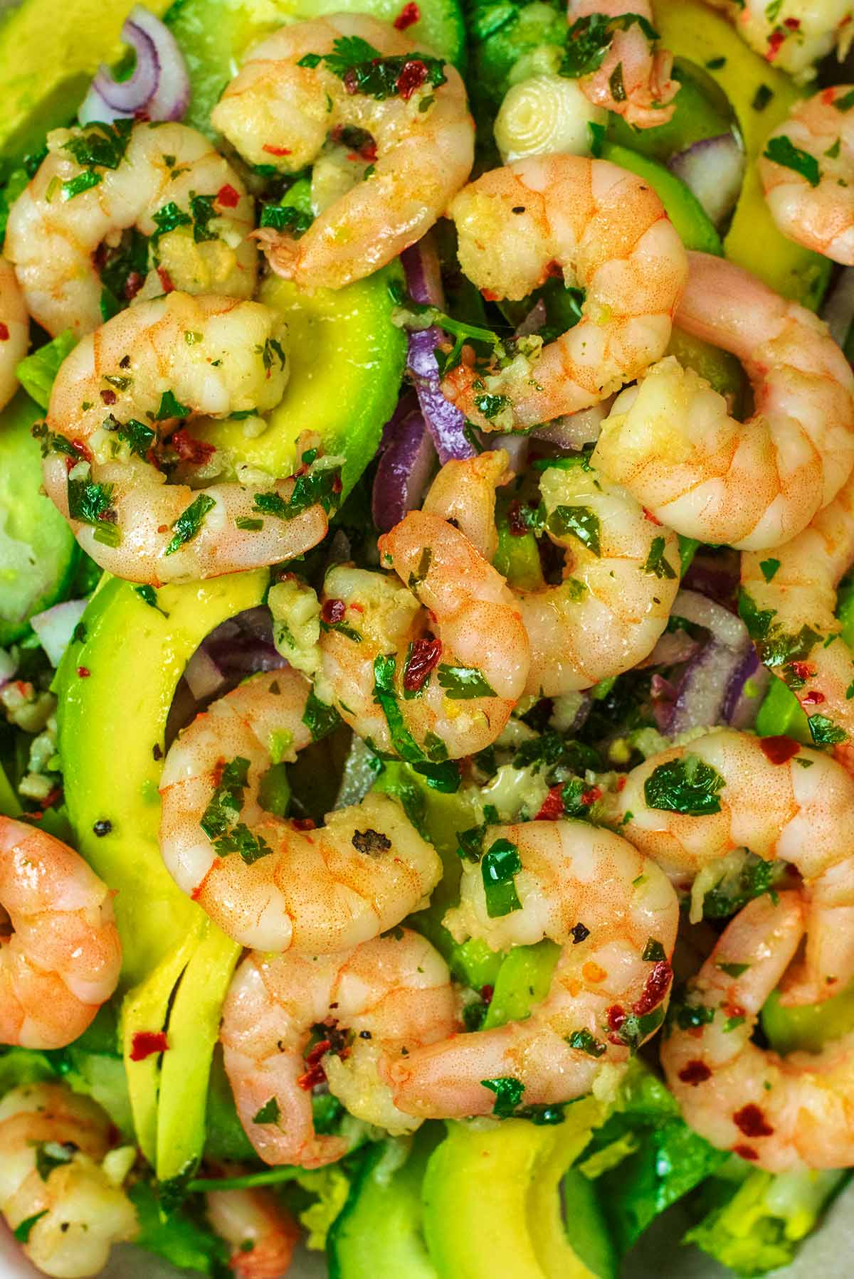 Marinated prawns on top of avocado and salad leaves.