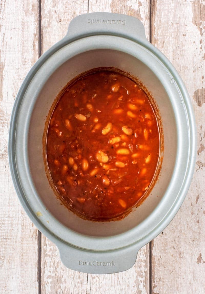 A slow cooker pot containing beans in a tomato sauce.
