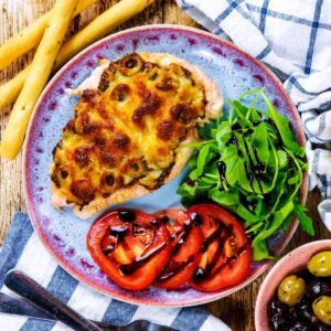 Pizza Chicken Breast on a plate with tomato slices and lettuce.