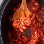 A serving spoon full of slow cooker baked beans.