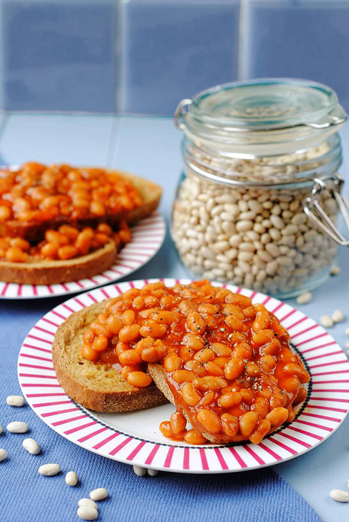 Two plates of beans on toast sat on a blue towel.