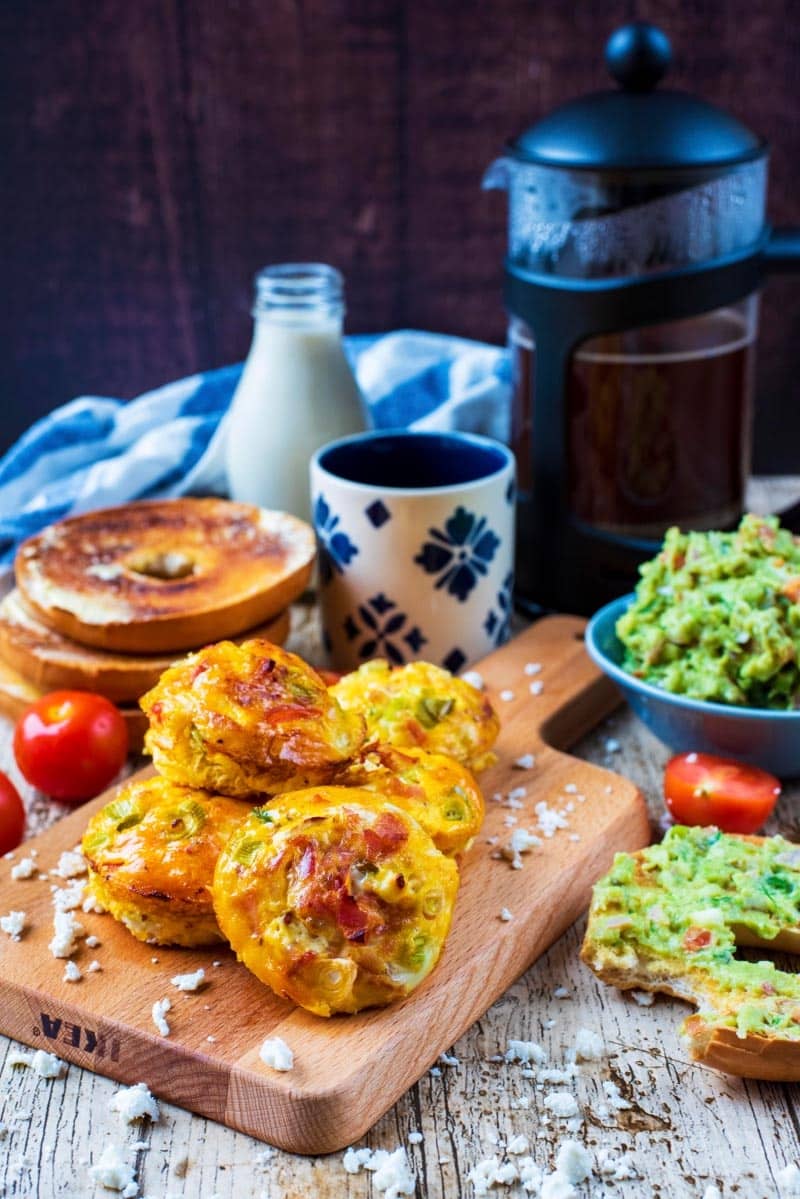 Egg Muffins in front of a pot of coffee with bagels and mashed avocado.