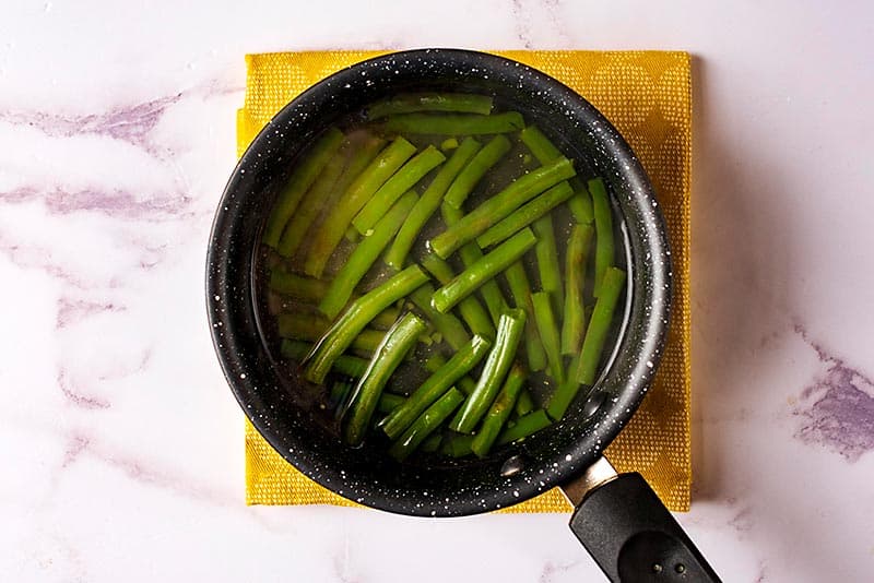 Green beans cooking in a saucepan.