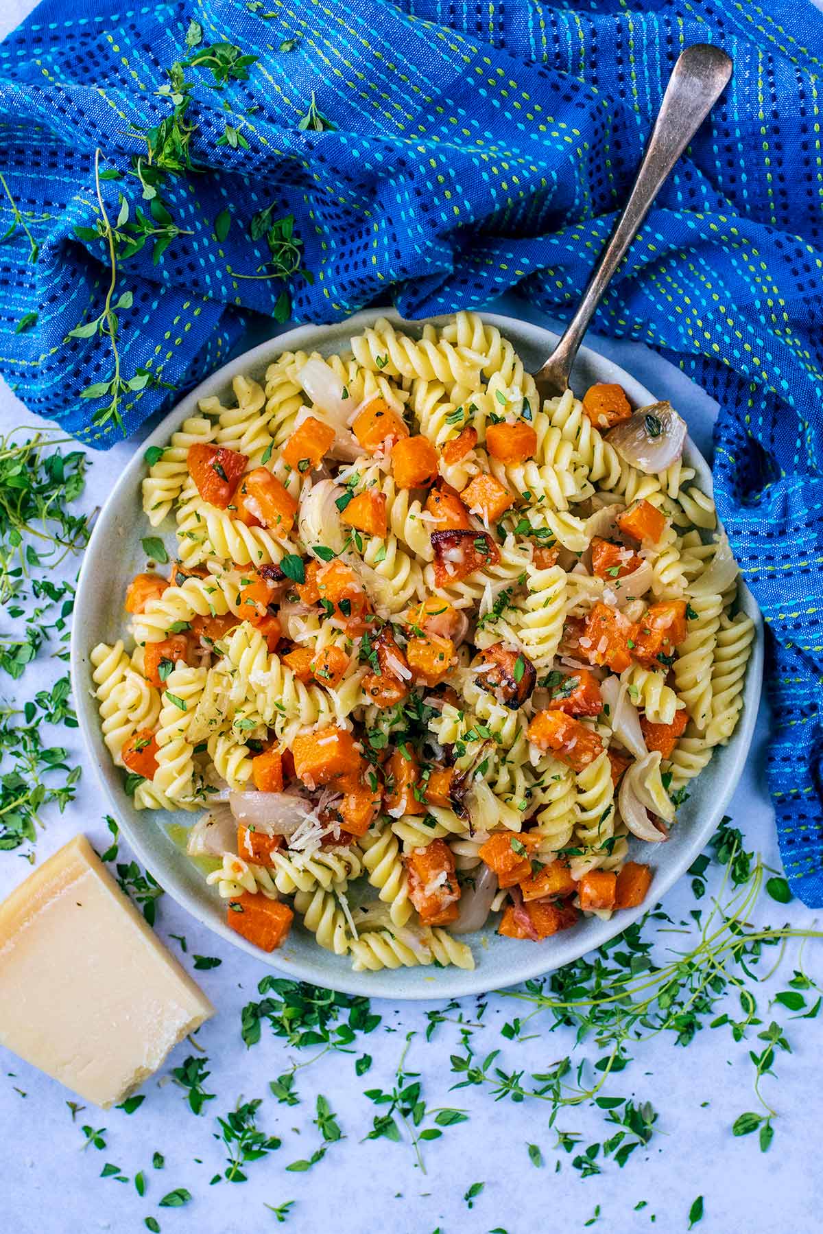 Cubes of butternut squash mixed into a bowl of cooked pasta.