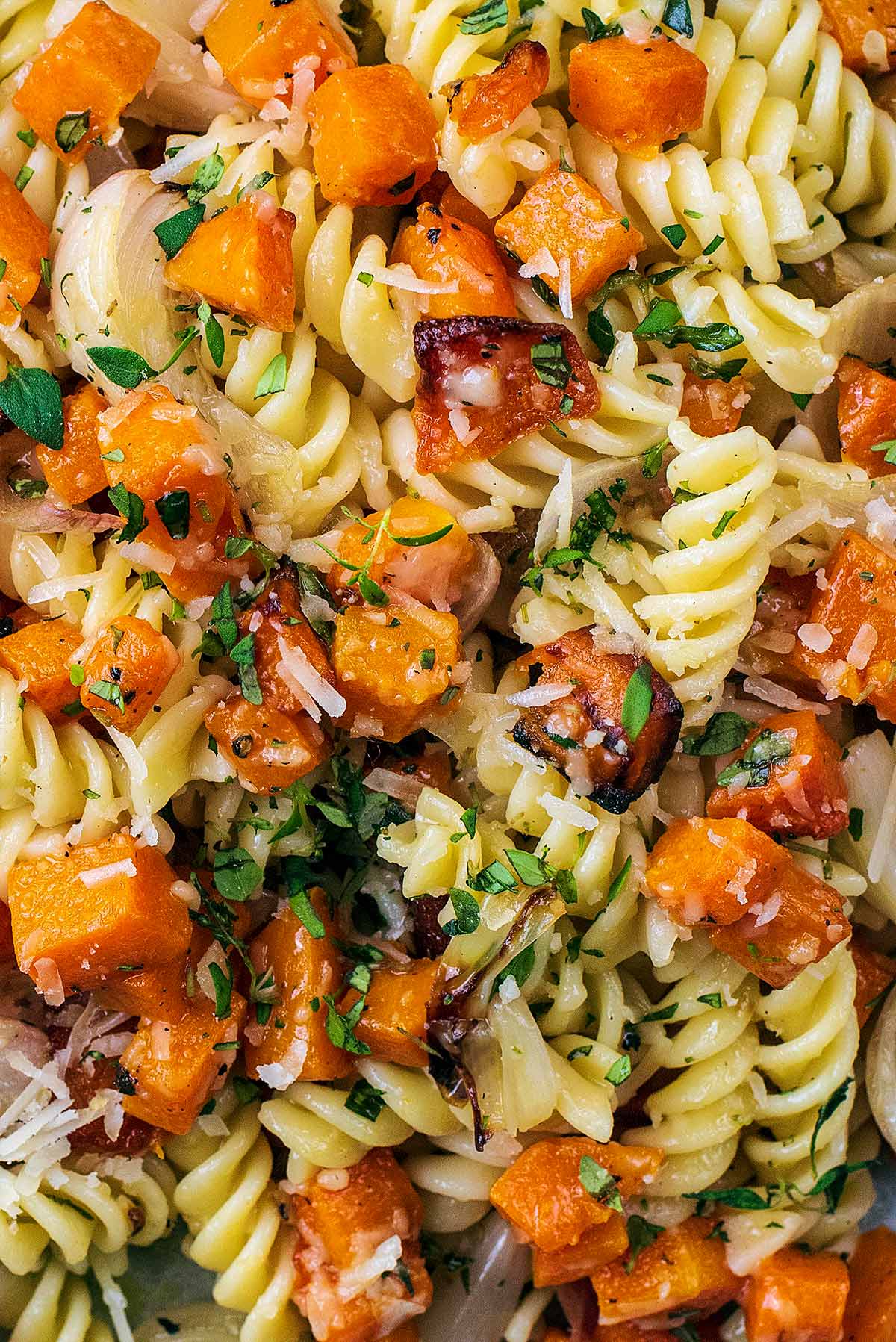 Cooked fusilli pasta, butternut squash and thyme leaves all mixed together.