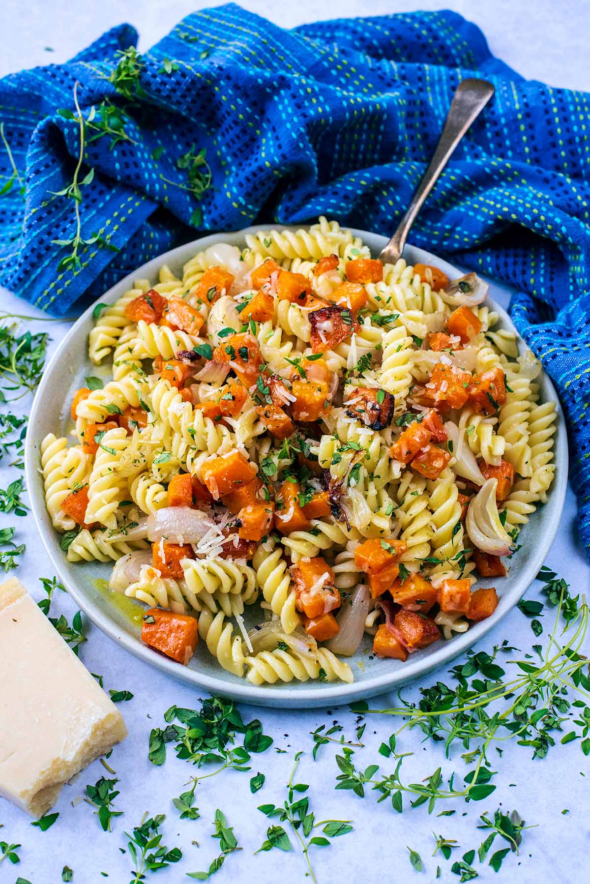 A bowl of butternut squash pasta in front of a blue towel.