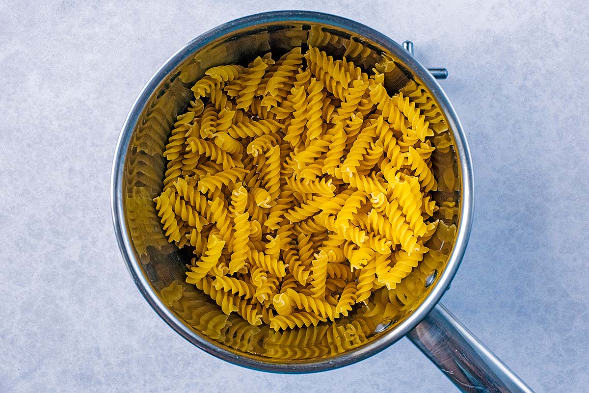 A saucepan containing uncooked fusilli pasta.