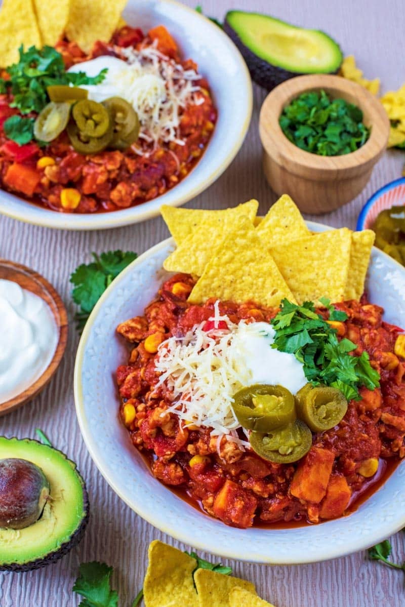 Chili in bowls with avocado, sour cream and cheese.