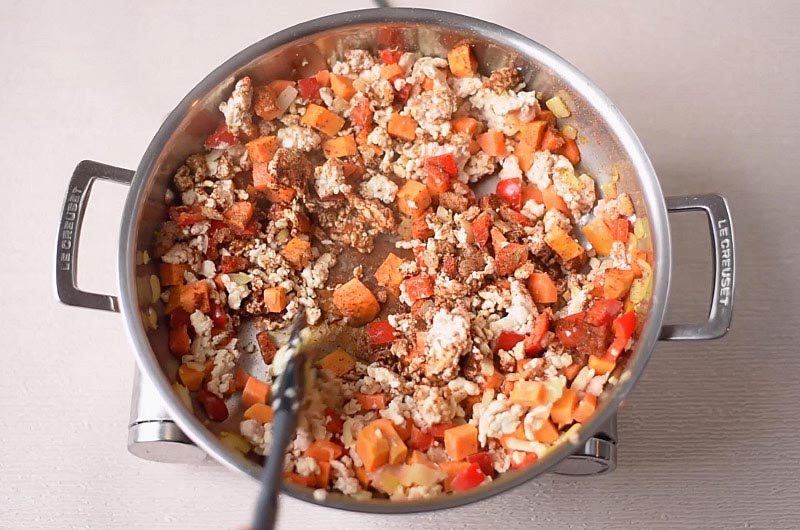 A large pan with cooked chopped vegetables, turkey mince and spices.