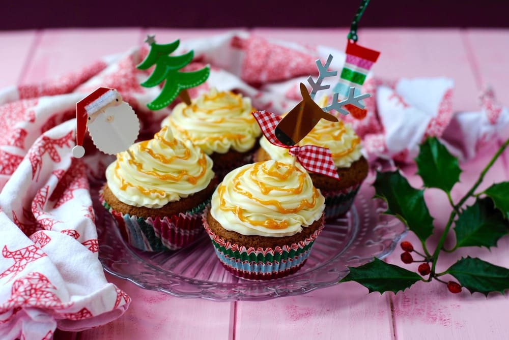 Four Gingerbread Cupcakes topped with frosting and Christmas decorations.