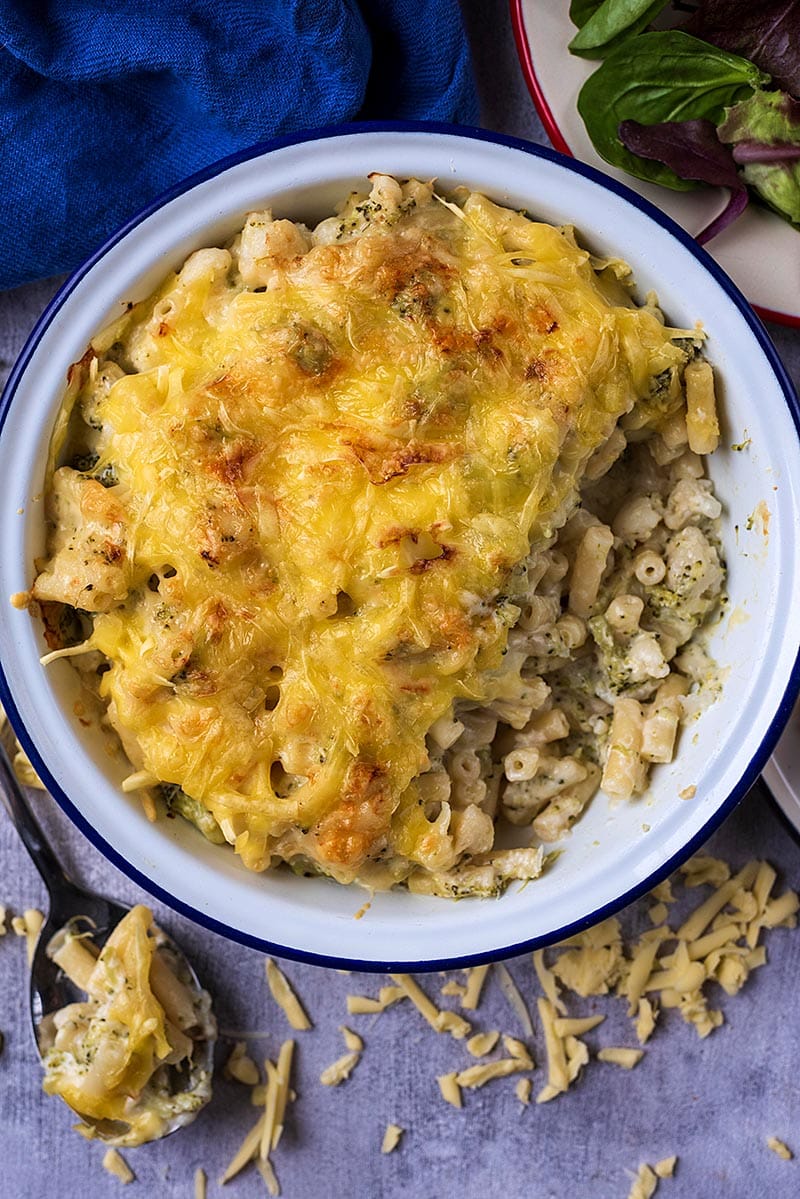 A baking dish containing mac and cheese. Some has been scooped out with a spoon