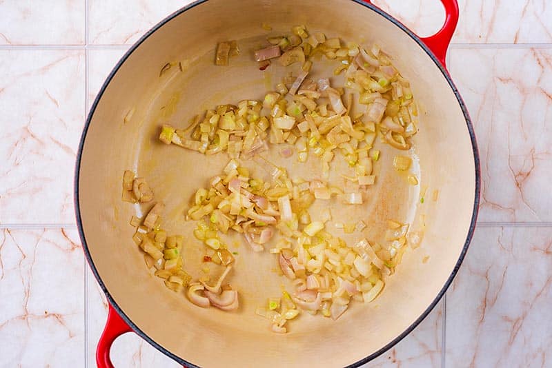 A large pan with chopped onions cooking in it.