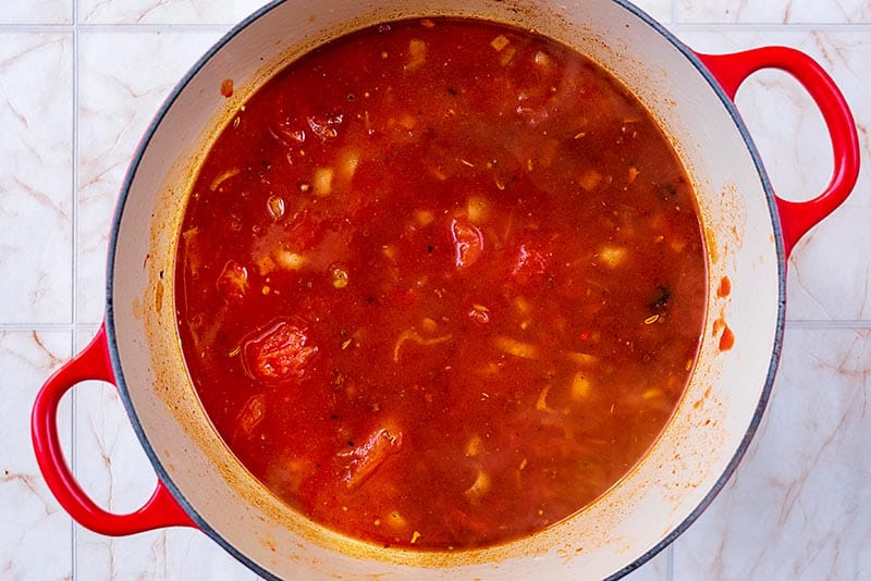 A large pan with a tomato sauce cooking in it.