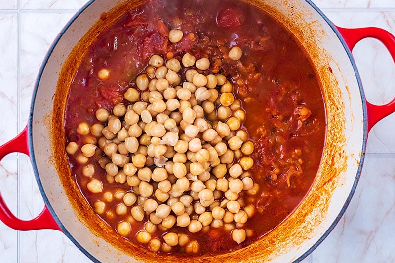 A large pan with a tomato sauce and chickpeas cooking in it.