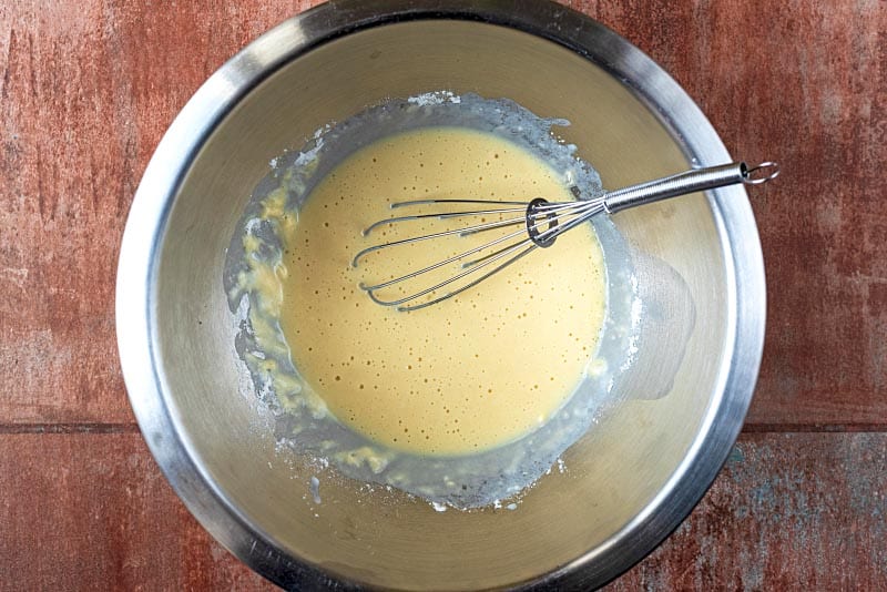 A mixing bowl containing whisked pancake batter.