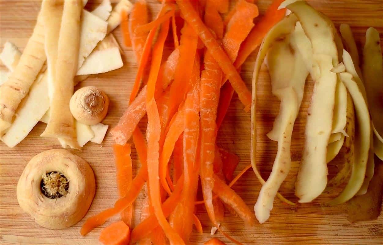 Parsnip, carrot and potato peelings on a chopping board.