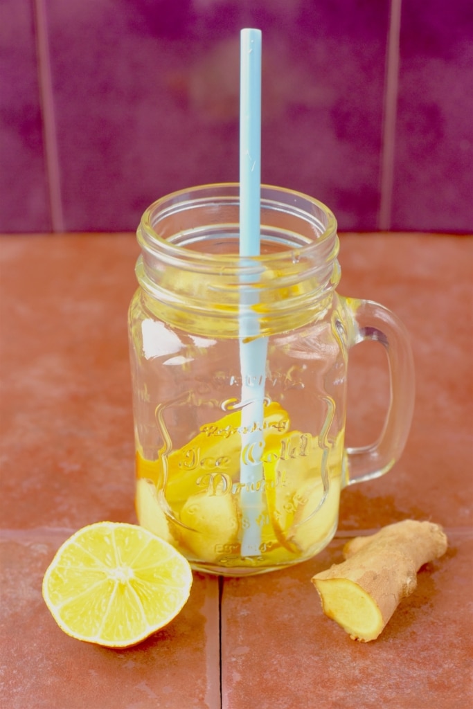A mason jar full of water with slices of lemon and ginger in it