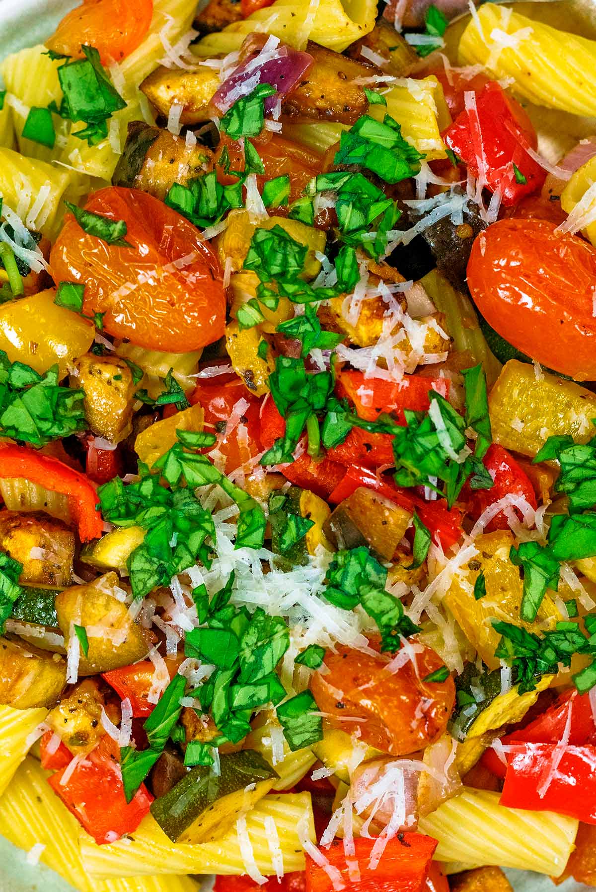 Cooked chopped vegetables mixed with pasta and topped with herbs and cheese.