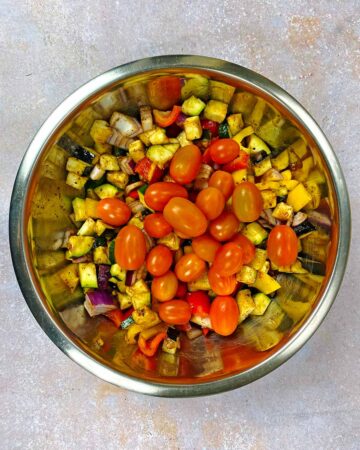 A large mixing bowl full of chopped vegetables and cherry tomatoes.