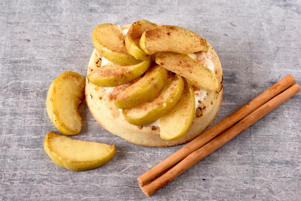 A Crumpet topped with sliced apple and cinnamon