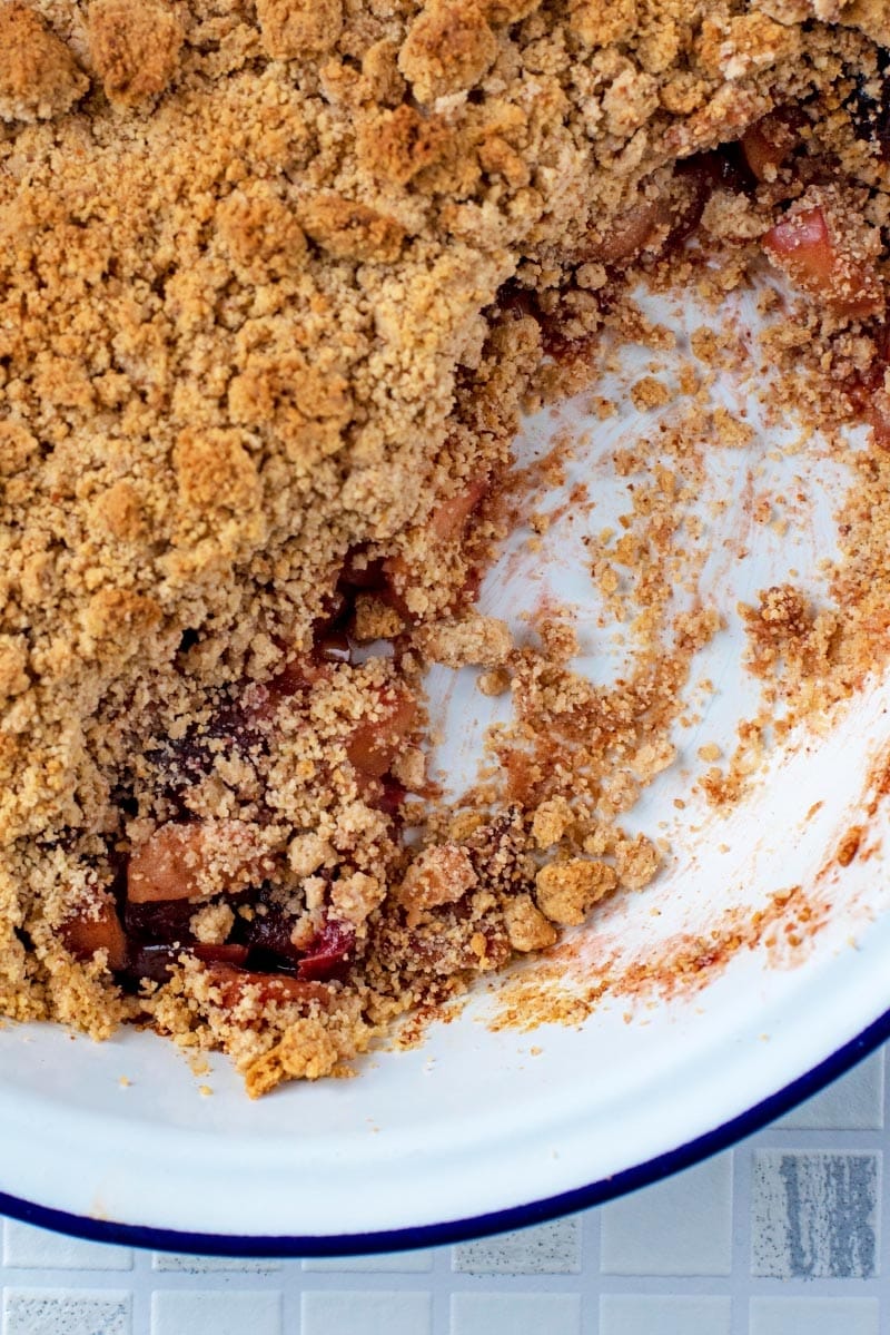 A dish of fruit crumble with a section removed.