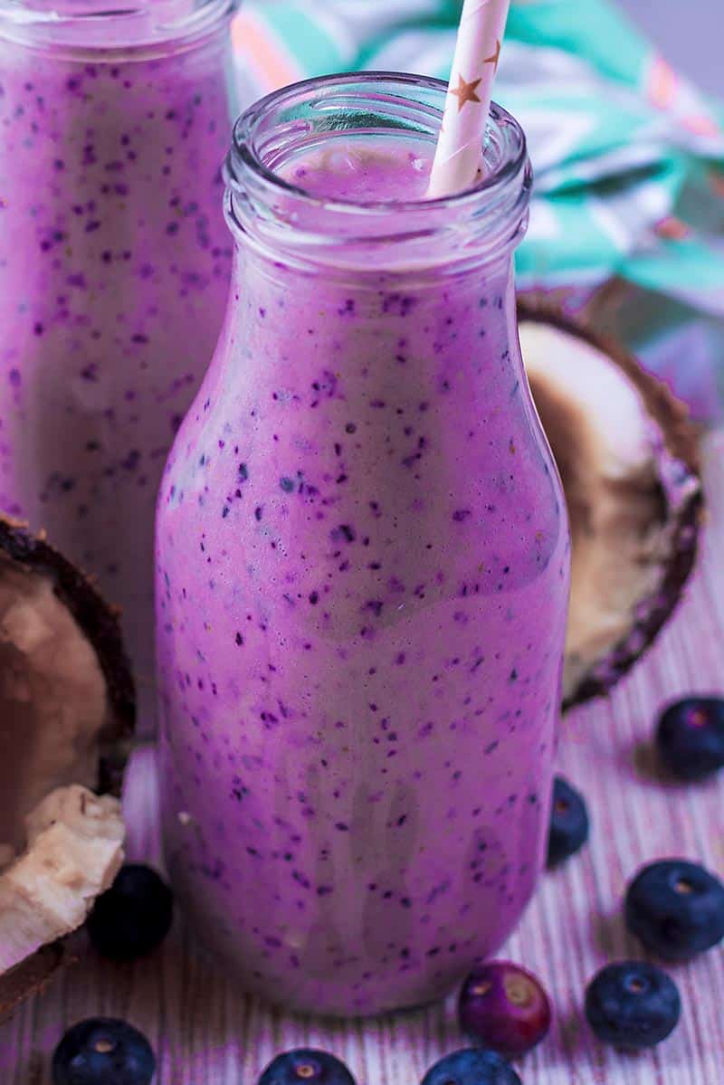 A bottle of purple smoothie with a drinking straw.