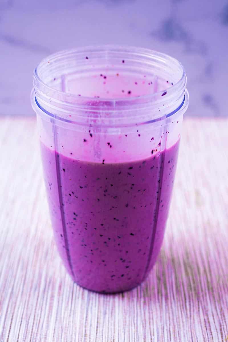 A blender jug containing a purple smoothie.