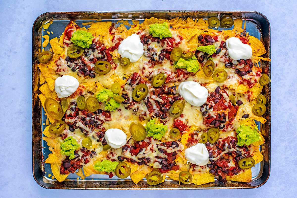 Cooked nachos with smashed avocado and dollops of creme fraiche added.