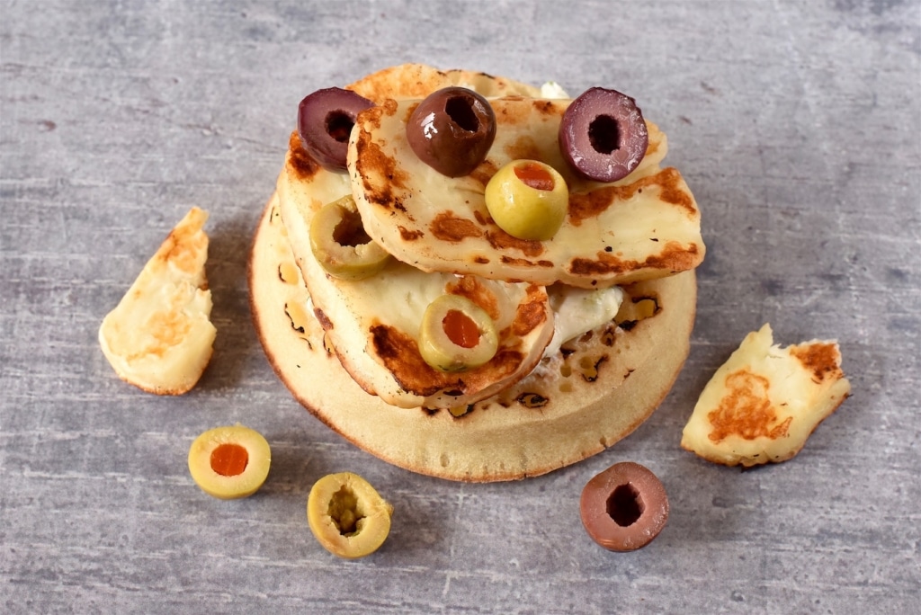 A Crumpet topped with tzatziki, halloumi and olives
