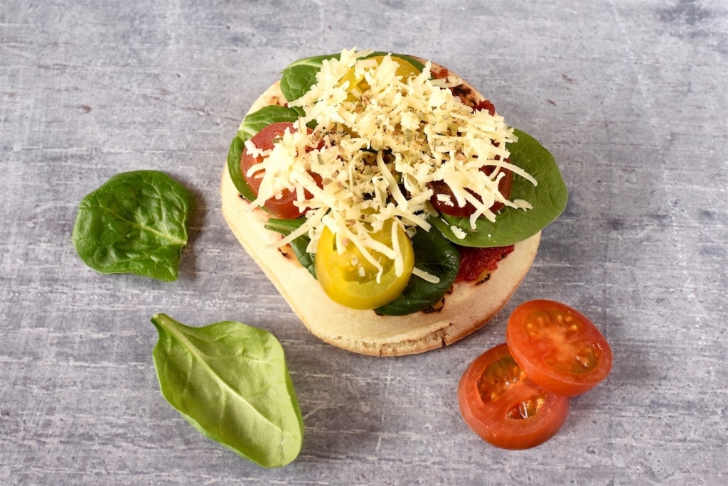 A Crumpet topped with cheese, tomato and spinach